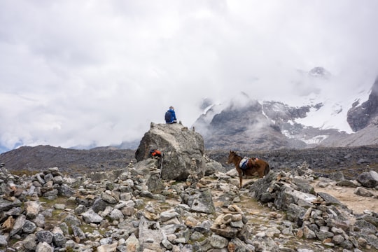 man wearing blue shirt sitting on rock in Salkantay Peru