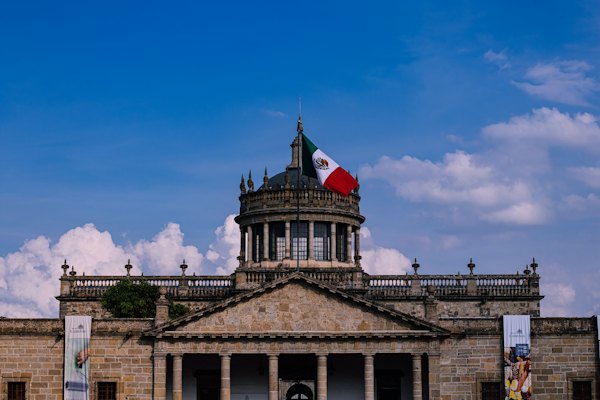 Brown concrete building with flag of Mexico — Guadalajara, Mexico