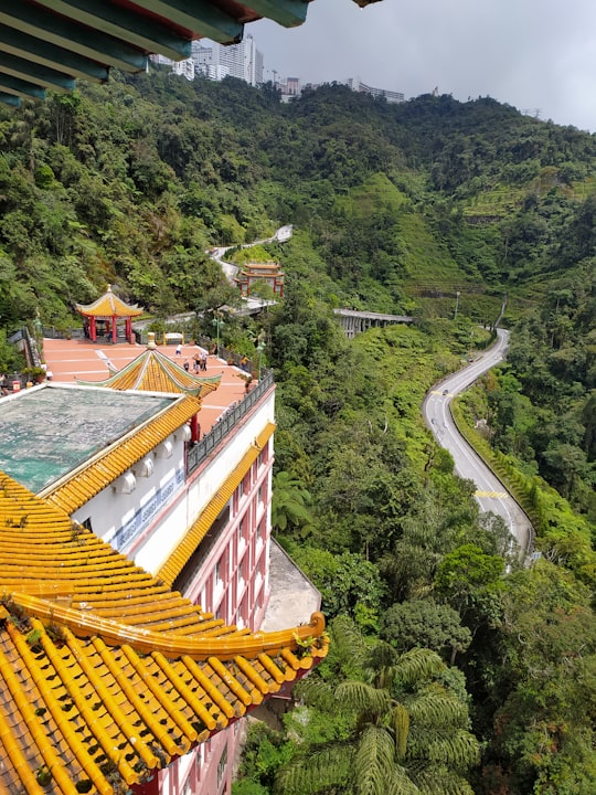 red and white concrete building beside trees during daytime in Chin Swee Caves Temple Malaysia