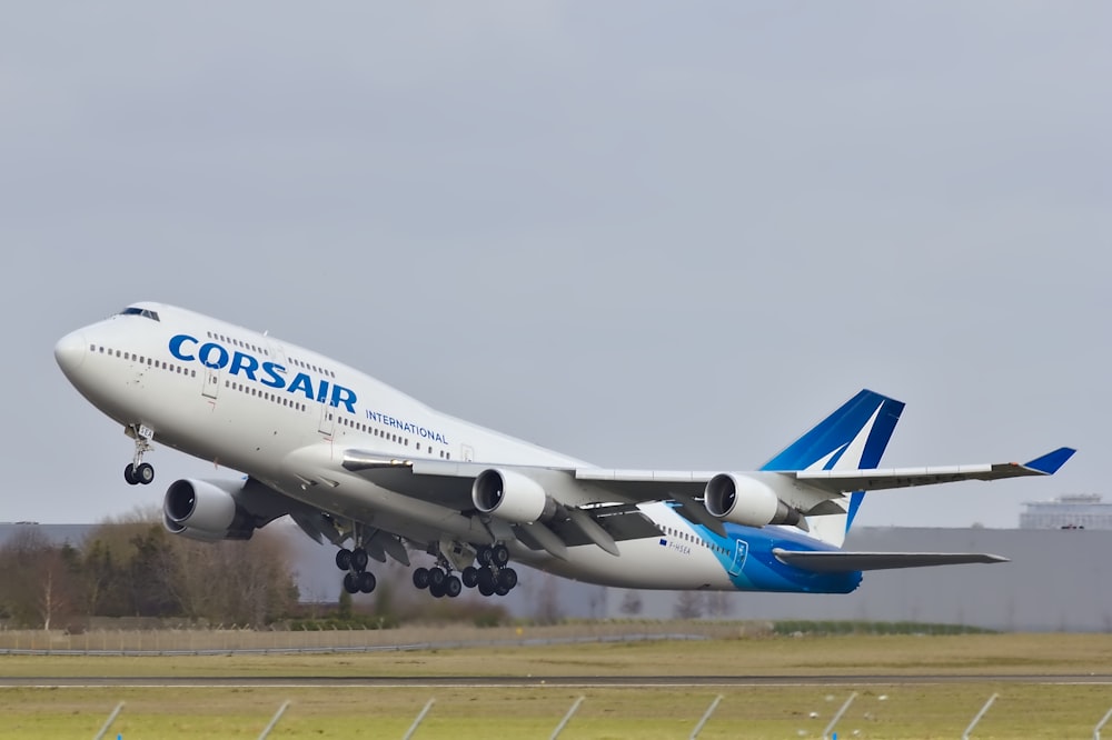 aereo passeggeri Corsair bianco e blu che vola sulla pista