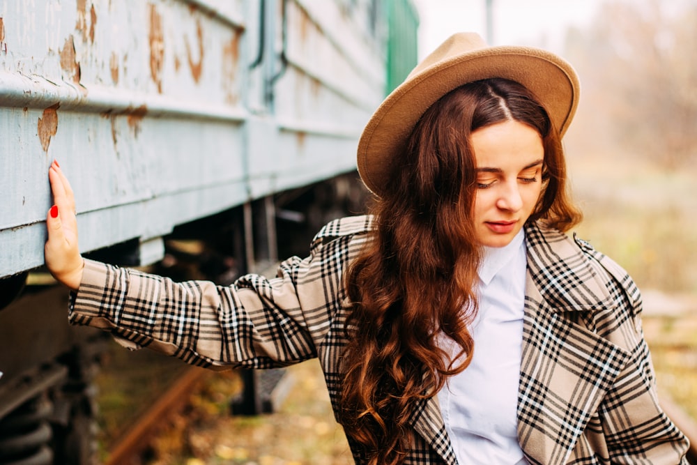 a woman wearing a hat leaning against a rail car