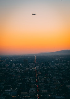 A panoramic cityscape at dusk with news helicopters flying overhead.