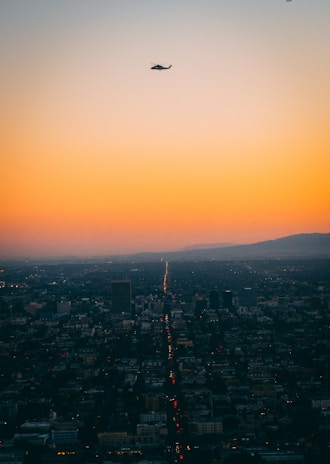 A panoramic cityscape at dusk with news helicopters flying overhead.