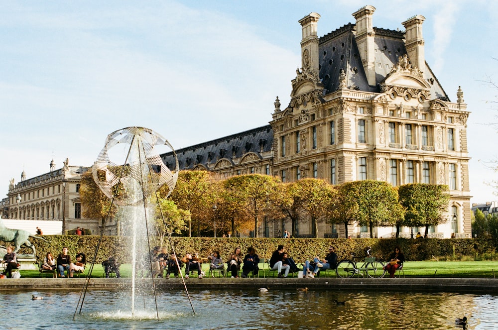 people sitting on bench beside water fountain during daytime