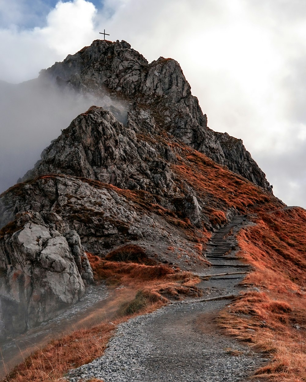 montagne brune et grise sous des nuages blancs