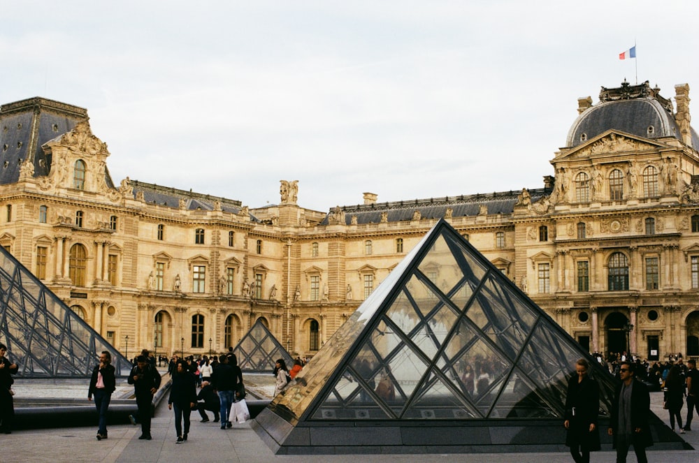 pessoas andando perto do Museu do Louvre durante o dia