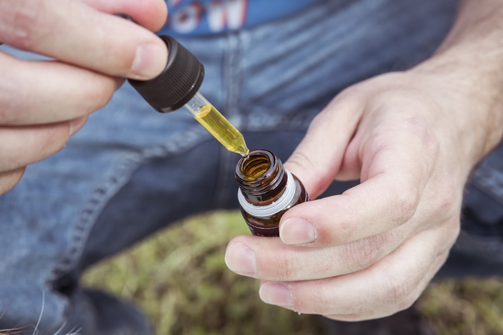 selective focus photography of person holding drop bottle