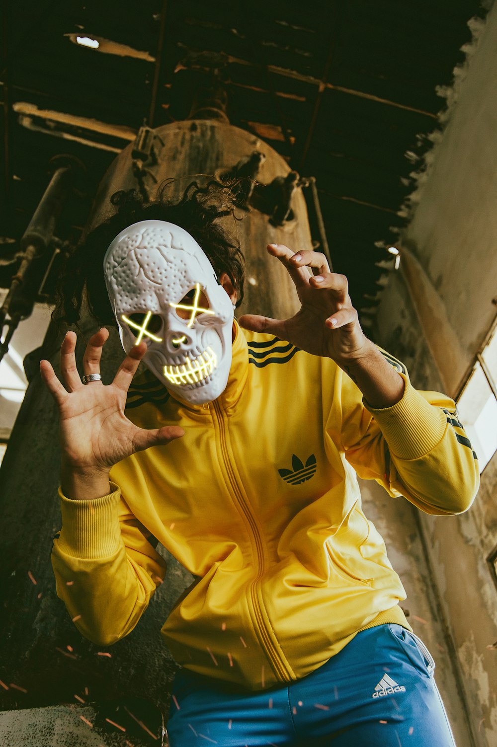 person in yellow adidas full-zip jacket wearing skull mask