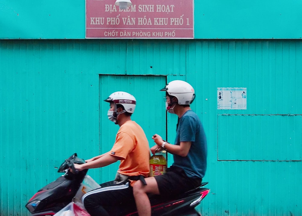 two men riding motor scooter