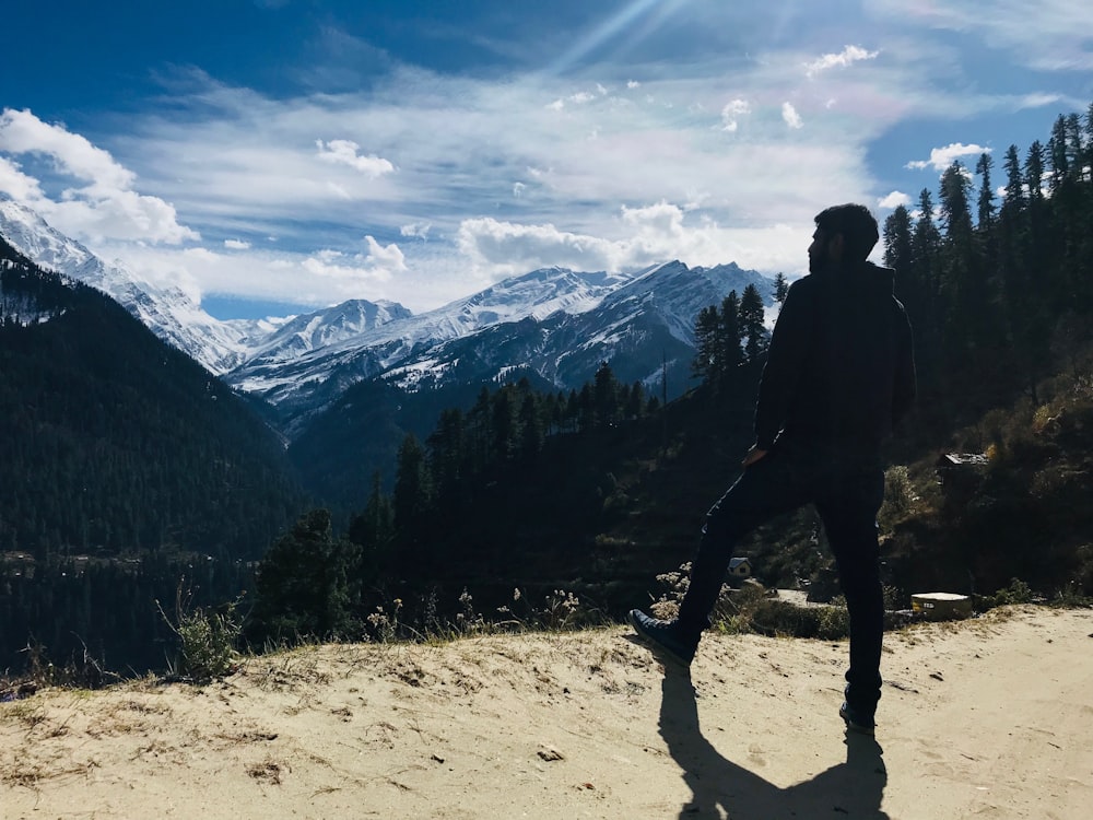 silhouette of man looking at icy mountain