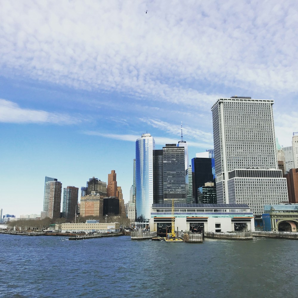 city with high-rise buildings near body of water under white and blue sky during daytime