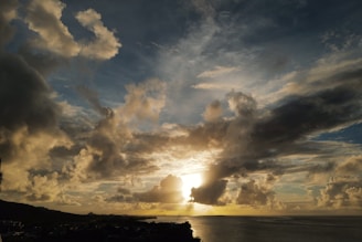 A dramatic cliffside view overlooking a vast ocean at sunset.