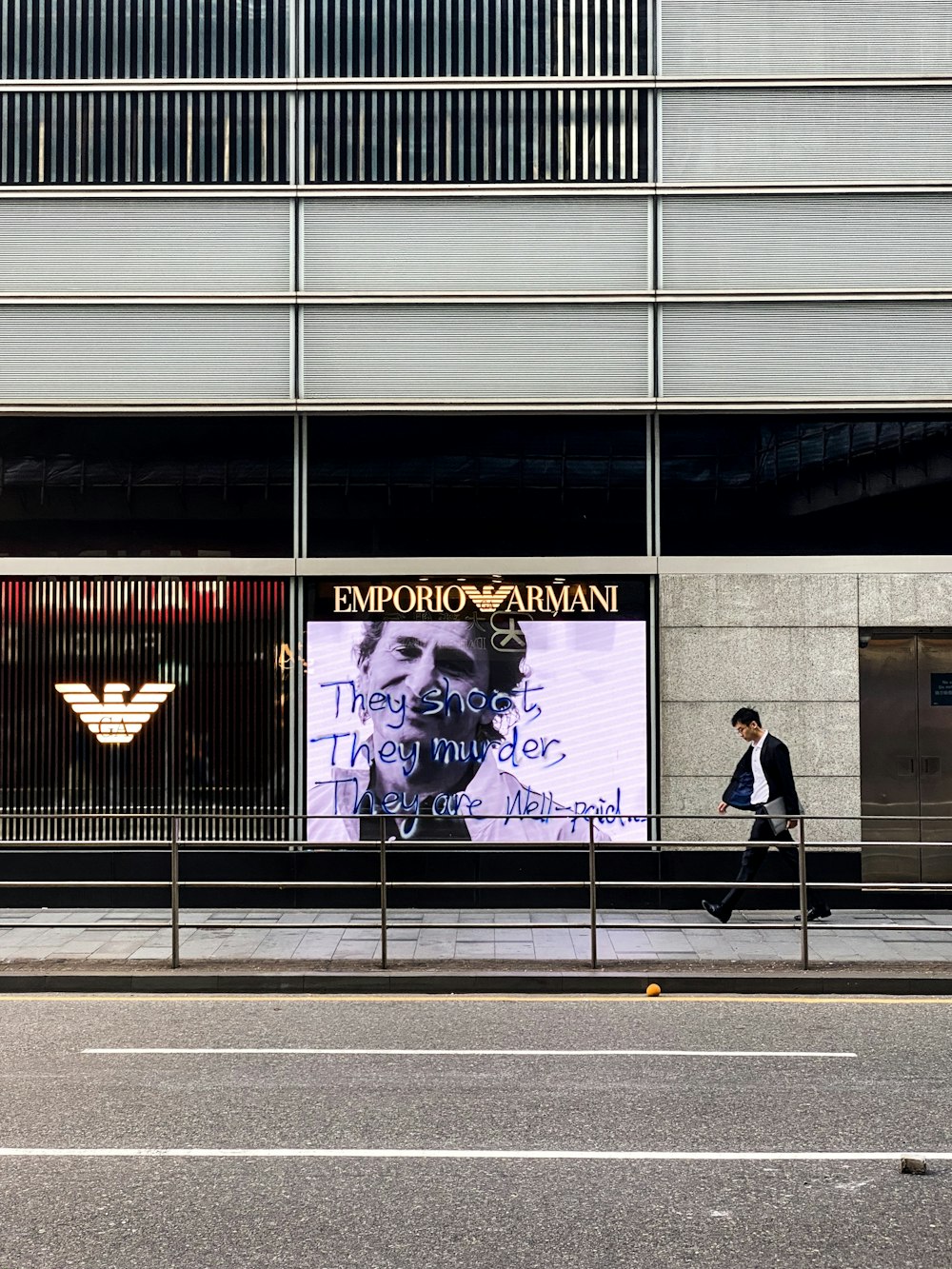 a man walking down a street past a tall building