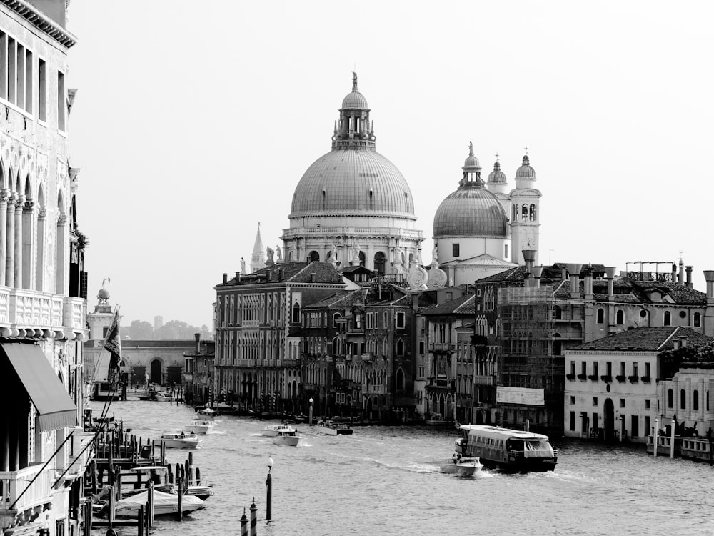 grayscale photography of passenger vessel passing by a canal in the city