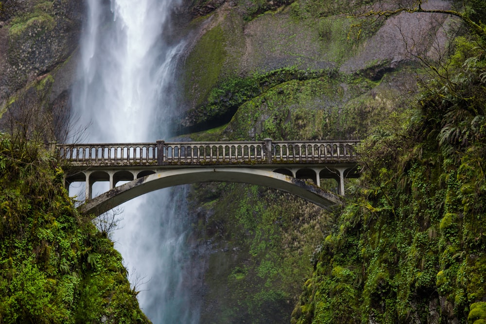 gray metal bridge beside waterfalls
