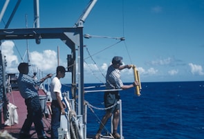 Crew members preparing equipment on deck with the vast ocean stretching beyond.