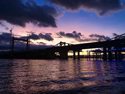 Heavy construction machinery working on a large modern bridge project at sunset.