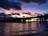A panoramic view of a bridge construction site at sunset with heavy machinery in use.