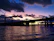 A panoramic view of a bridge construction site at sunset with heavy machinery in use.
