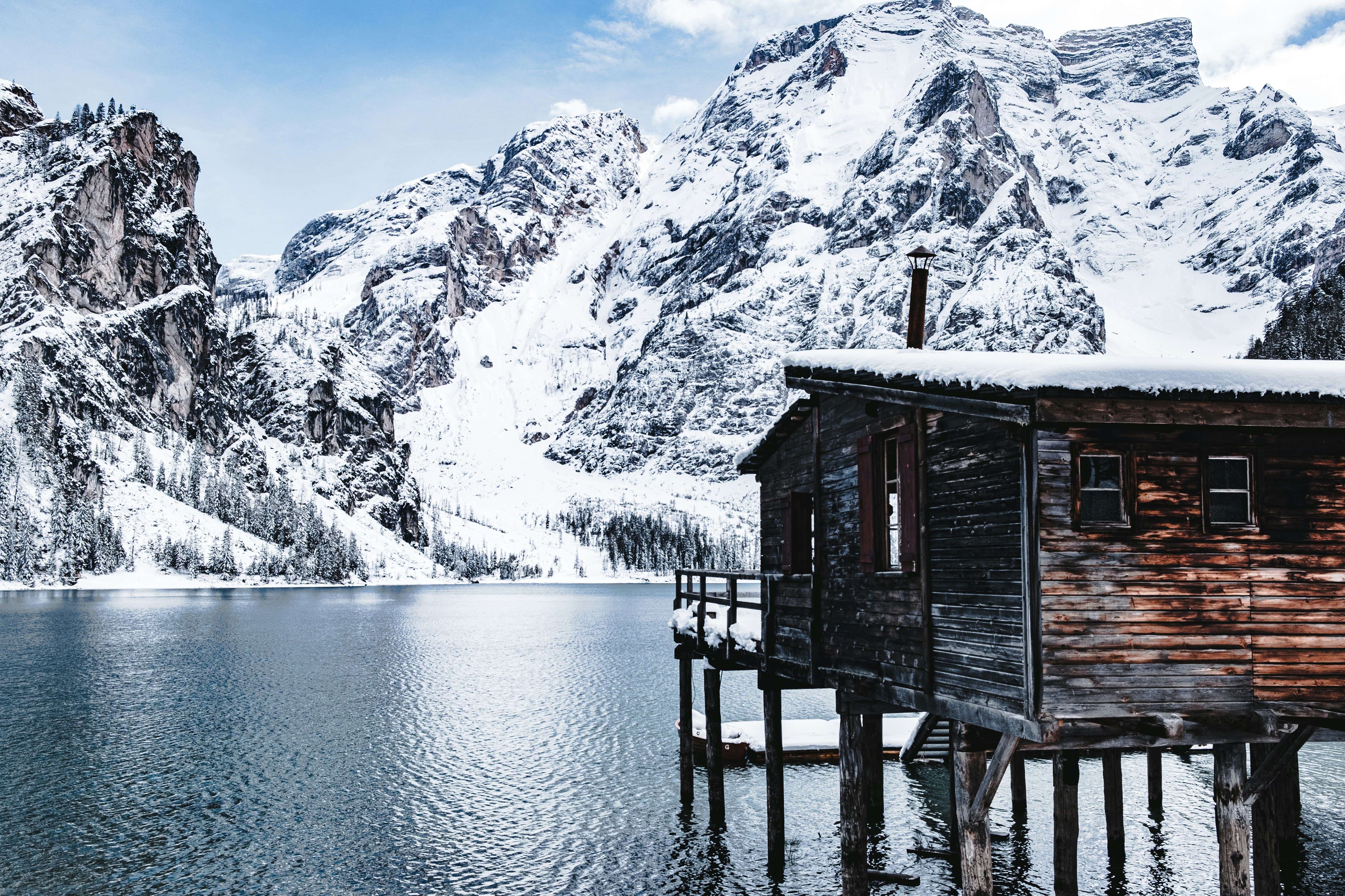 brown stilt house above water near glacier mountains