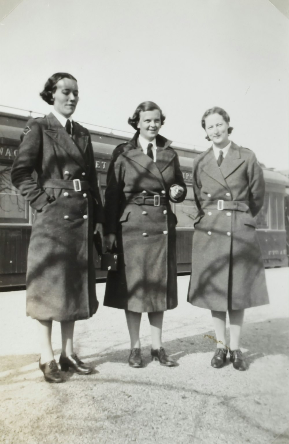 코트를 입은 세 여자의 회색조 사진