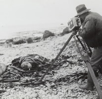 grayscale photography of man taking photo near seashore