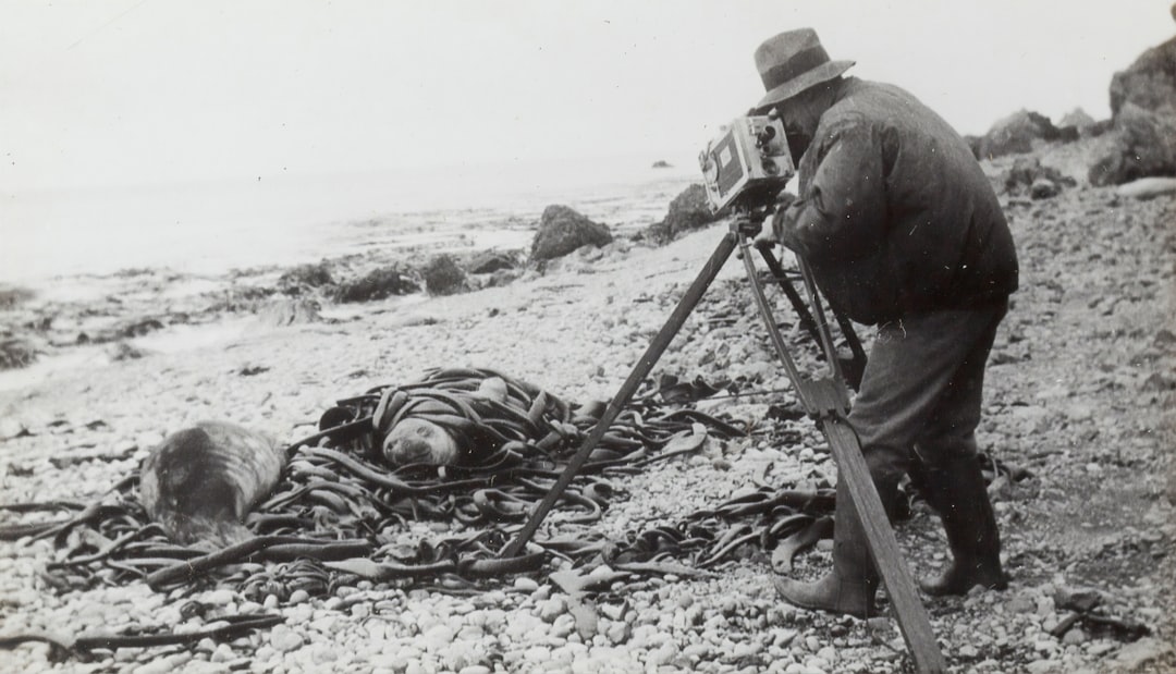 grayscale photography of man taking photo near seashore