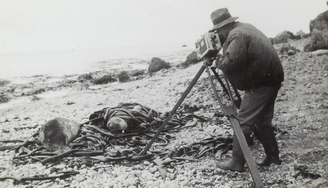 grayscale photography of man taking photo near seashore,