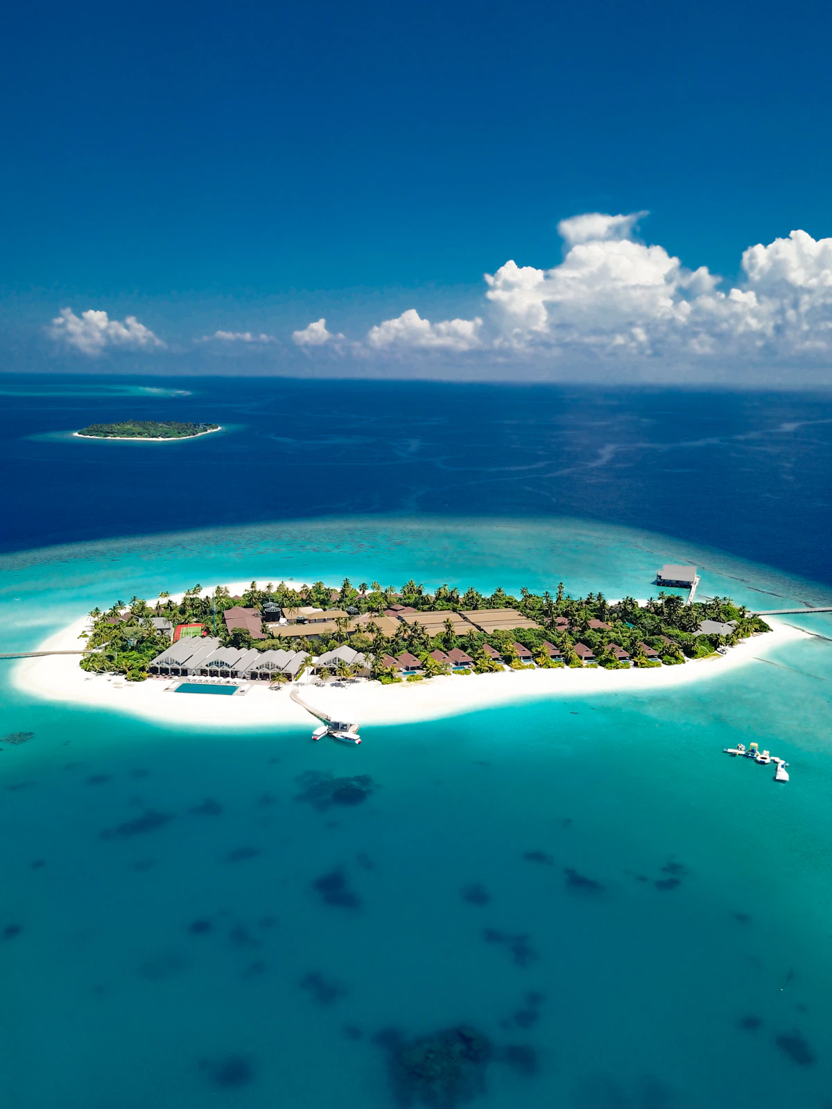 Maldivian island and reef seen from the air, ringed by deep blue ocean