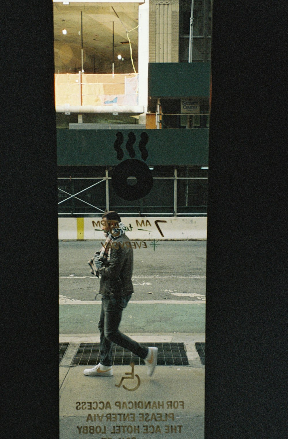 a man walking down a sidewalk next to a tall building