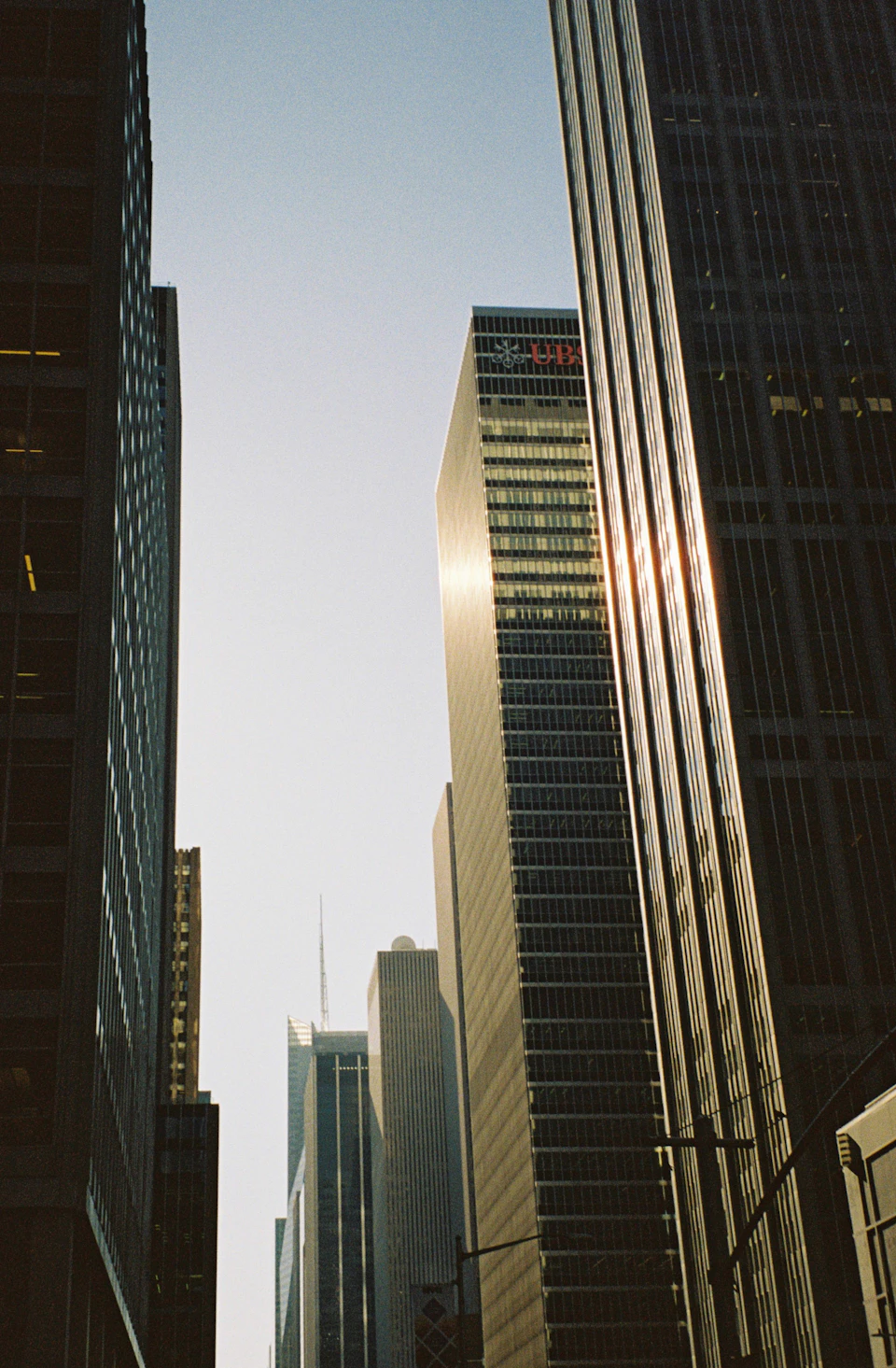 Bustling city street lined with modern buildings under clear blue sky with tall skyscrapers