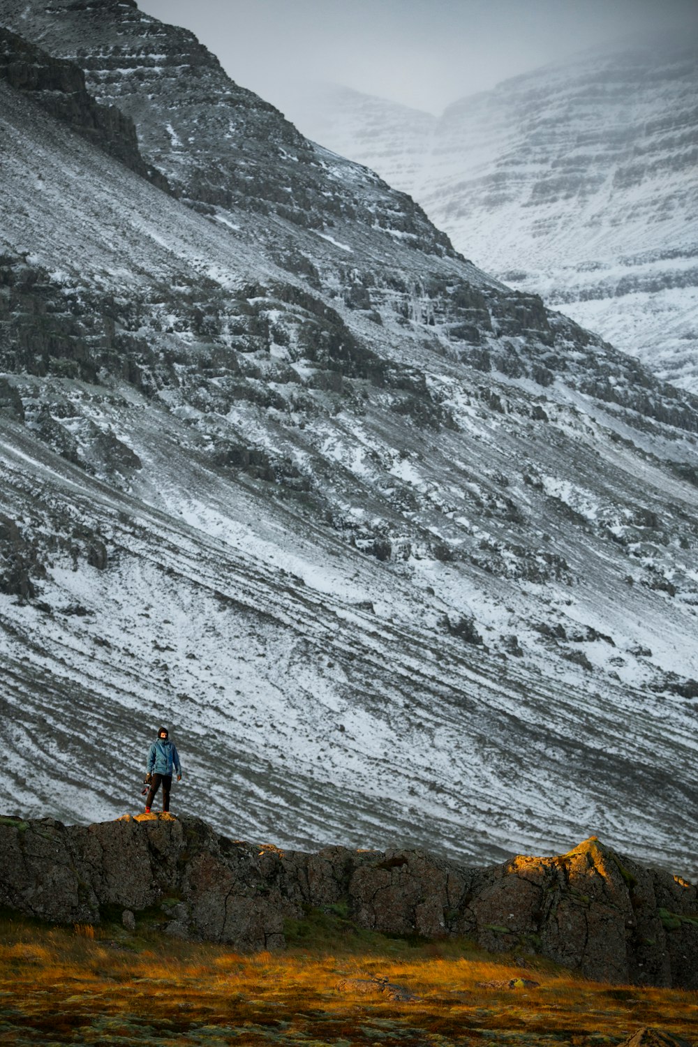 person standing beside grey mountain during daytime