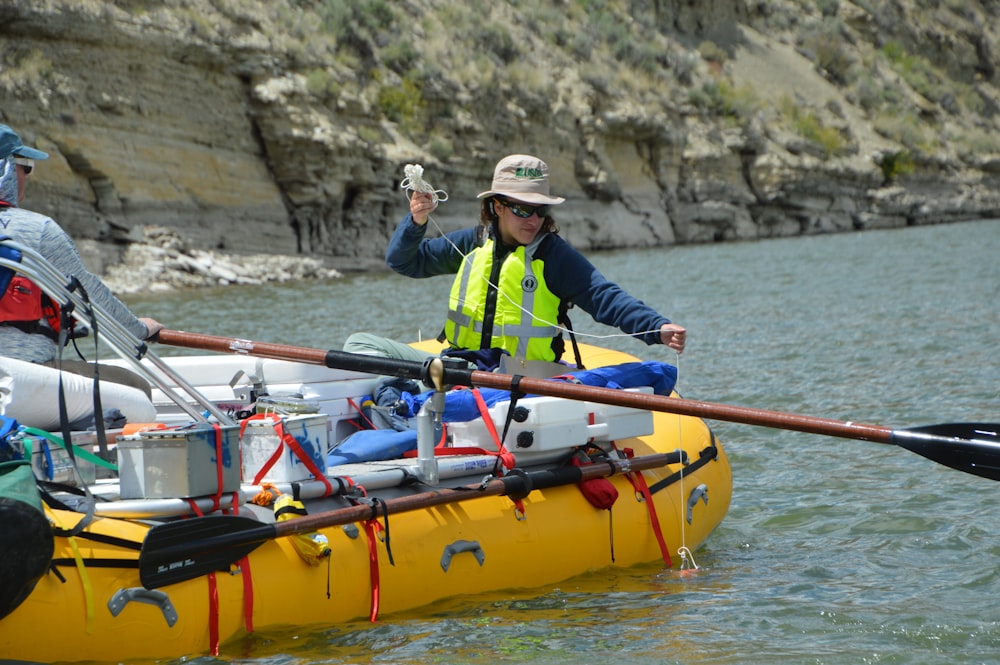 man wearing green safety vest riding yellow inflatable boat