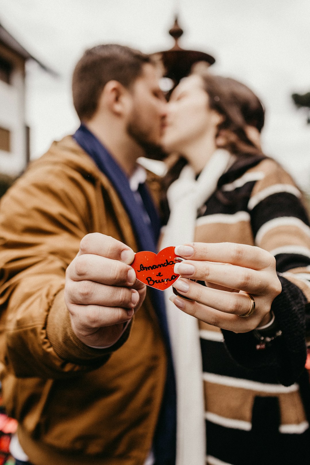 woman and man kissing while holding red and black heart deocr