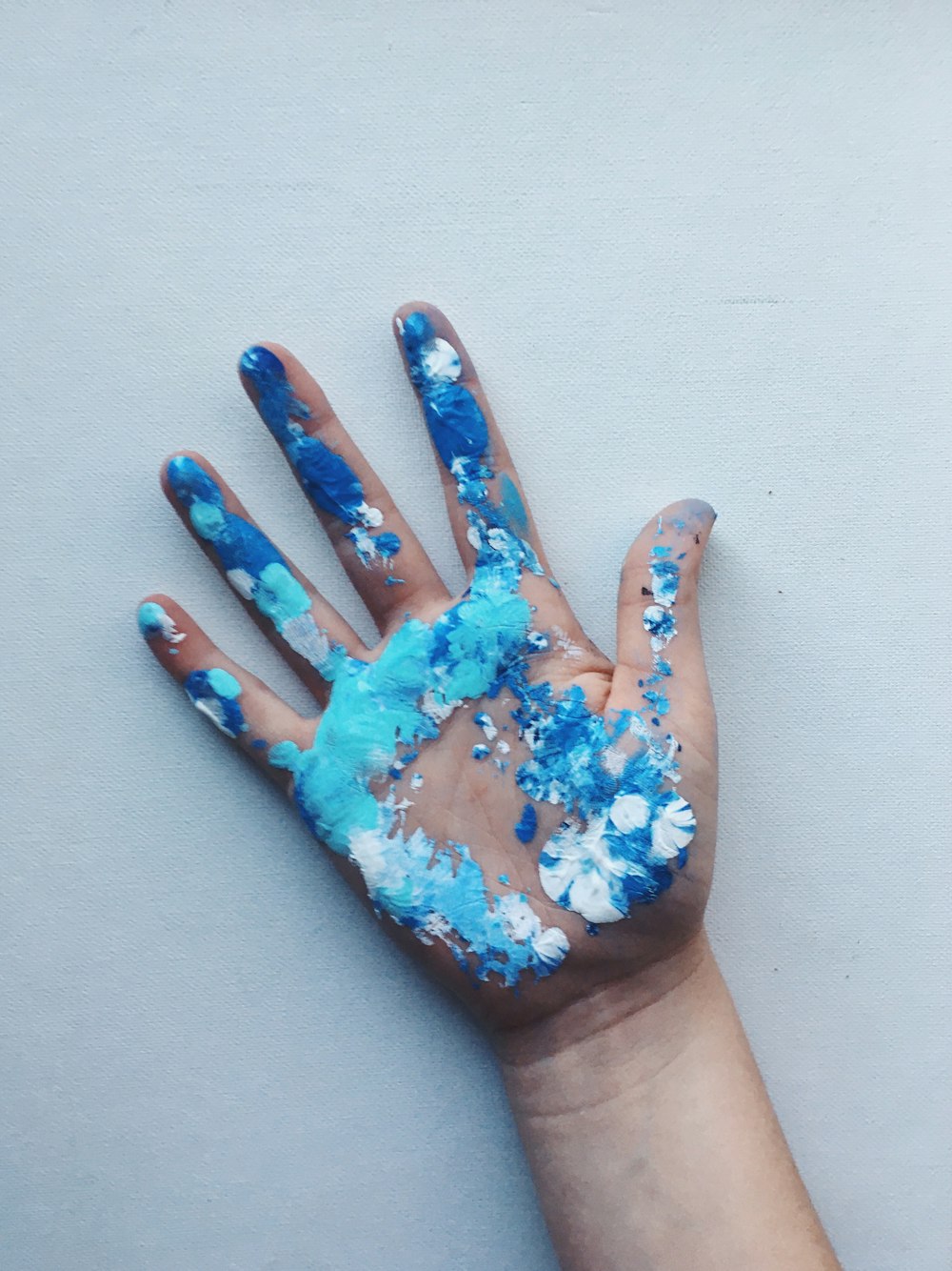 파란색과 흰색 페인트를 칠한 오른쪽 인간의 손