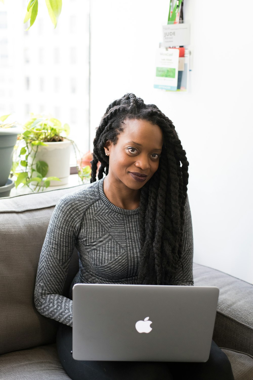 woman sitting and smiling with MacBook on her lap