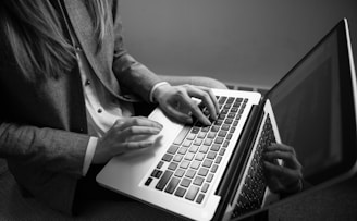 grayscale photography of woman typing on a laptop