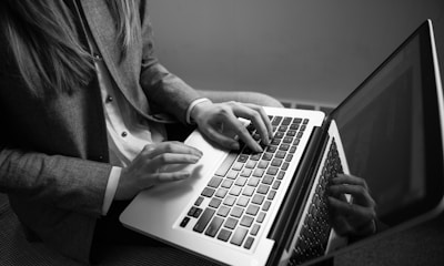 grayscale photography of woman typing on a laptop