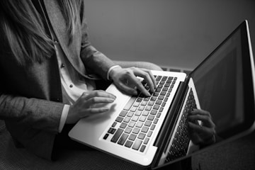 grayscale photography of woman typing on a laptop