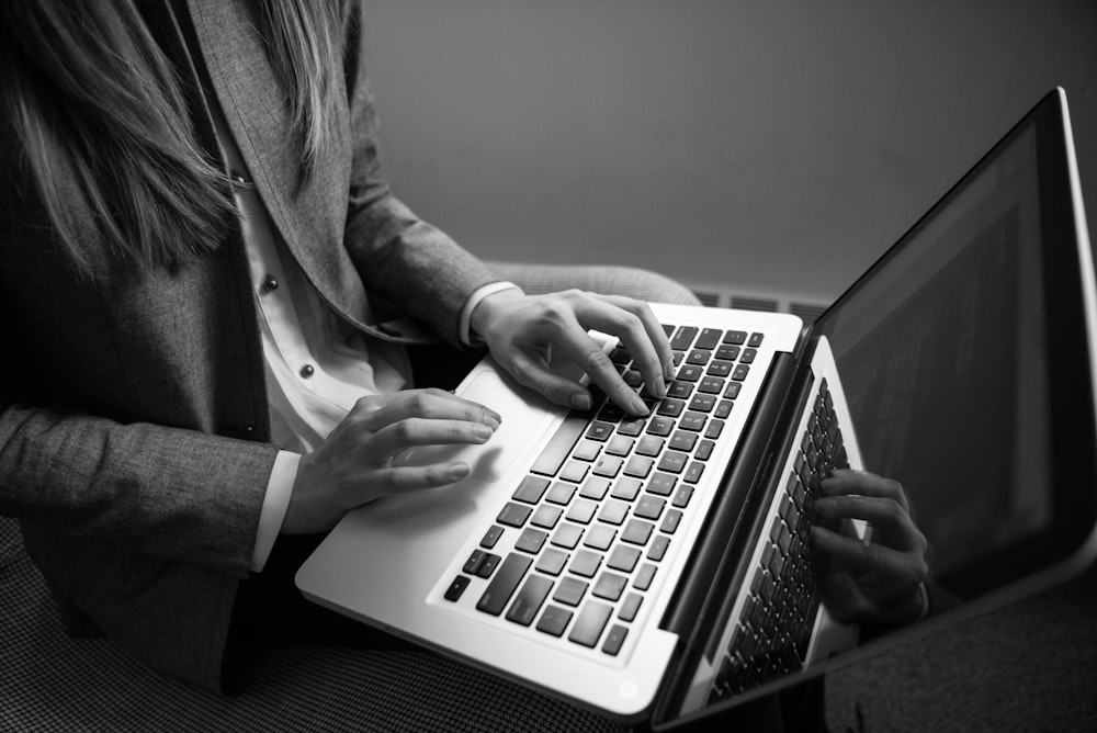 fotografia em tons de cinza da mulher digitando em um laptop