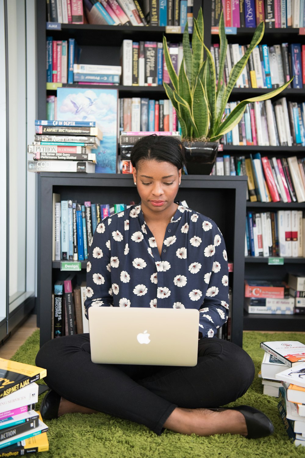 woman sitting on rug using MacBook