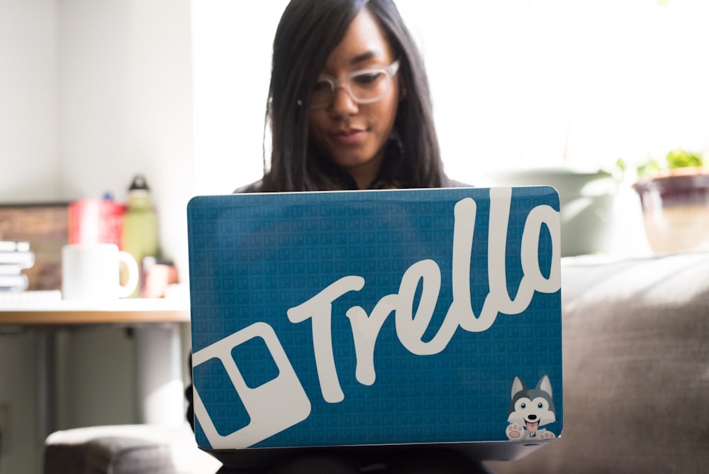 woman using laptop with blue and white trello sticker