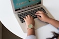 person using MacBook on white table