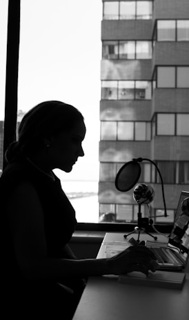 grayscale photography of woman sitting in front of a computer