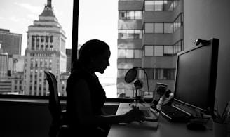 grayscale photography of woman sitting in front of a computer