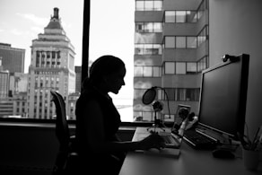 grayscale photography of woman sitting in front of a computer