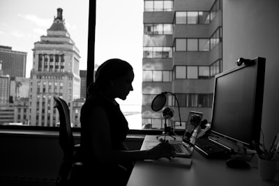 grayscale photography of woman sitting in front of a computer
