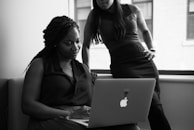 A mentor guiding a woman through computer skills on a laptop.