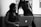 Two women are in an office setting looking at a laptop. One is seated and focused on the screen while the other stands beside her, leaning slightly over, with one hand on her hip. Natural light from a window illuminates the room, giving the photo a professional atmosphere.