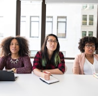 three women sitting at a table with a laptop